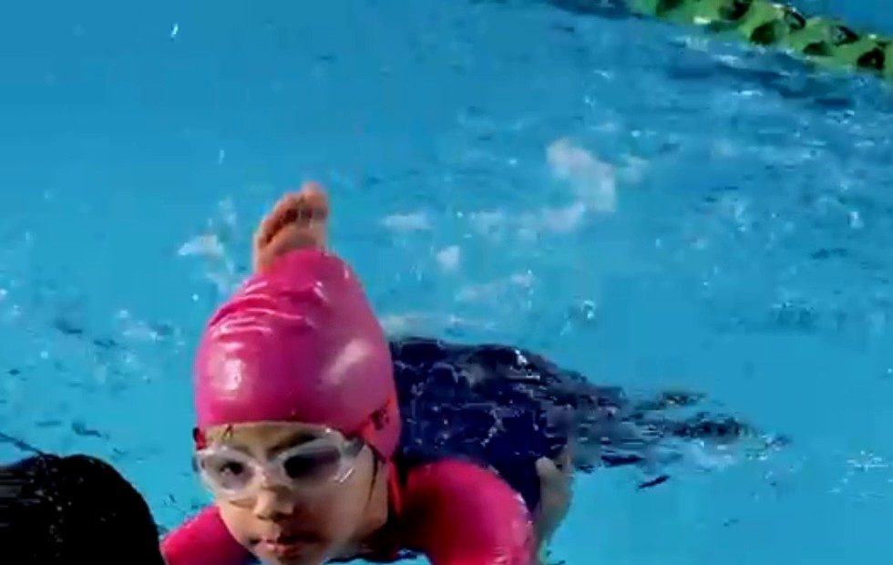 Child swimming with coach support in the pool
